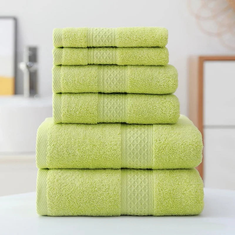 Stack of green towels on a white surface with a blurred bathroom background