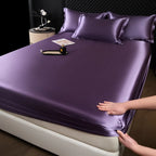 Purple satin sheet set on a bed with a person adjusting it.