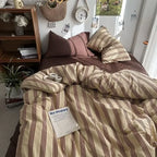 Bed with striped bedding and pillows in a cozy room setting.