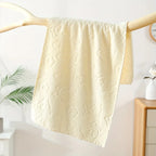 Beige textured towel hanging on a wooden rack against a white wall.