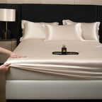 Silk mattress cover being unrolled on a bed with a perfume bottle on top.