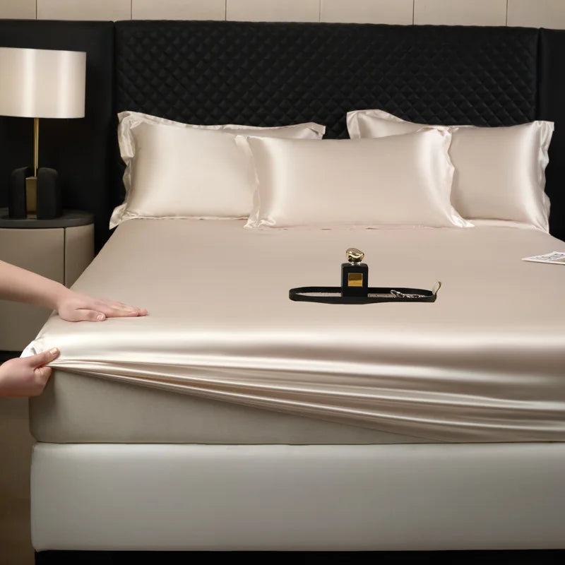 Silk mattress cover being unrolled on a bed with a perfume bottle on top.