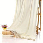 White curtain with lace trim draped over a stack of folded towels on a white background