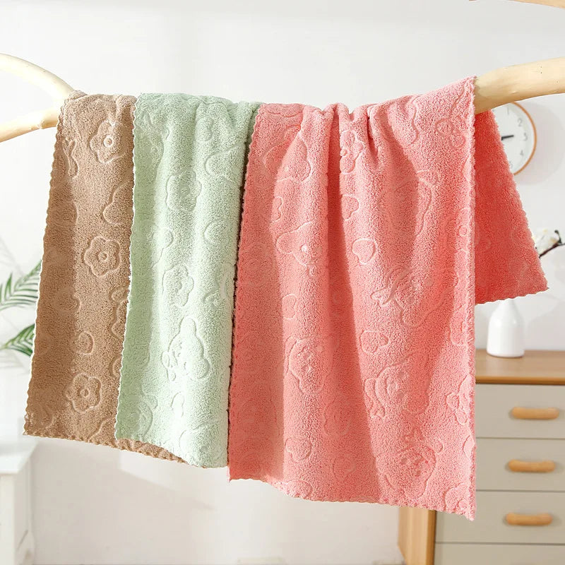 Three textured towels in beige, green, and pink hanging on a rack.