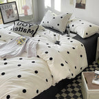 Bed with polka dot bedding and pillows in a room setting.