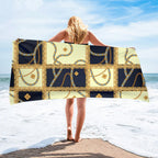 Person holding a decorative towel on a beach with ocean and sky in the background