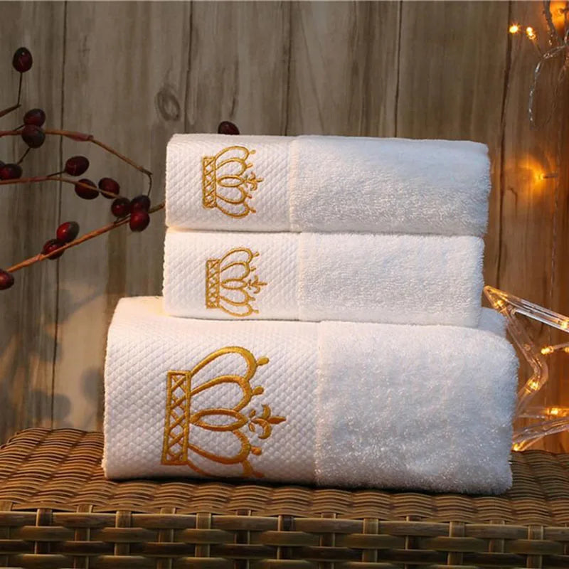 Set of white towels with gold embroidery on a wooden surface