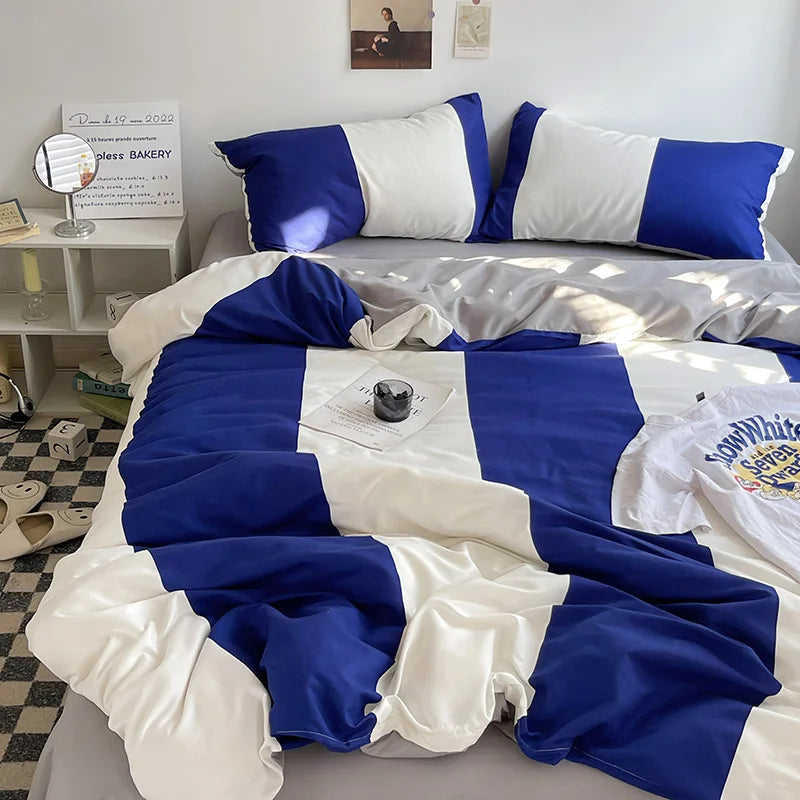 Blue and white bedding set on a bed in a room with a mirror and desk.