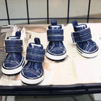Pair of blue denim dog boots on a metal surface.