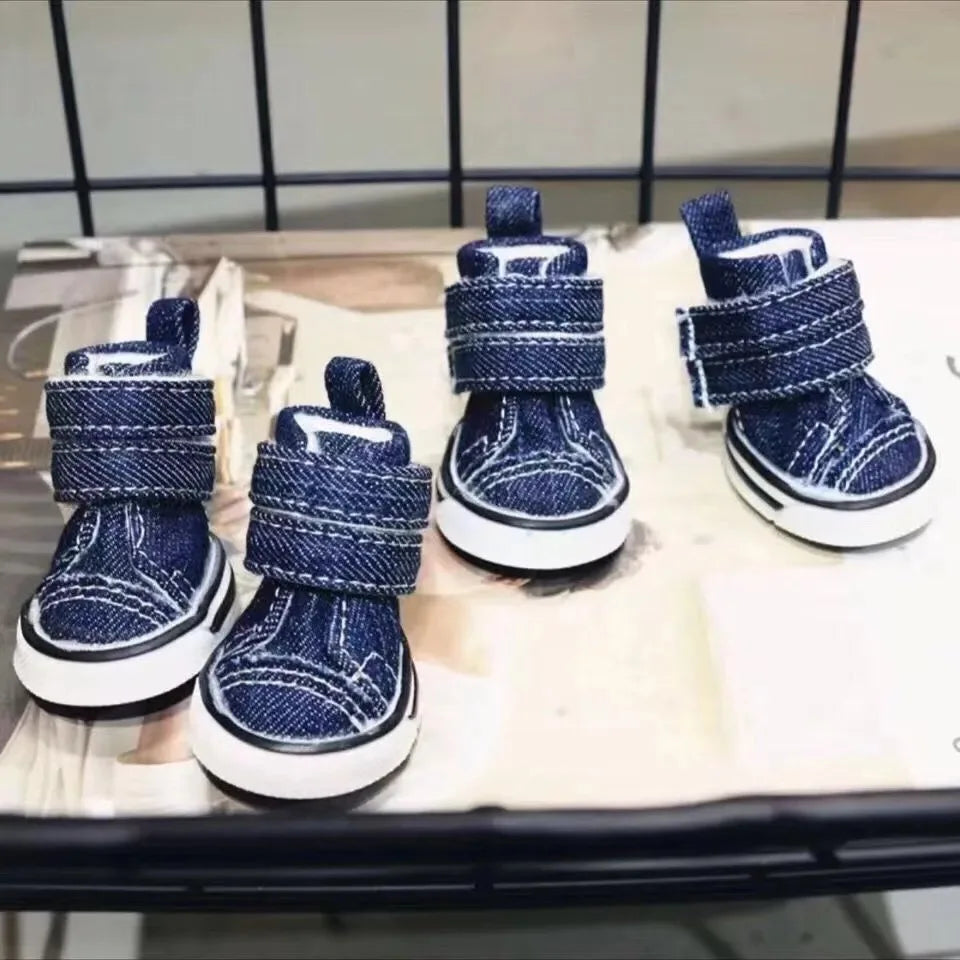 Pair of blue denim dog boots on a metal surface.