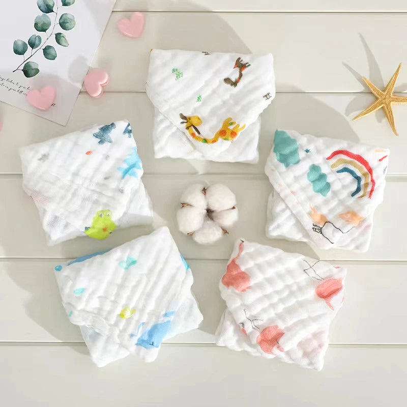 Set of baby bibs with colorful designs on a wooden surface with cotton and decorative elements.