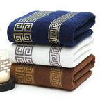 Stack of three folded towels with decorative patterns in blue, white, and brown on a white background.