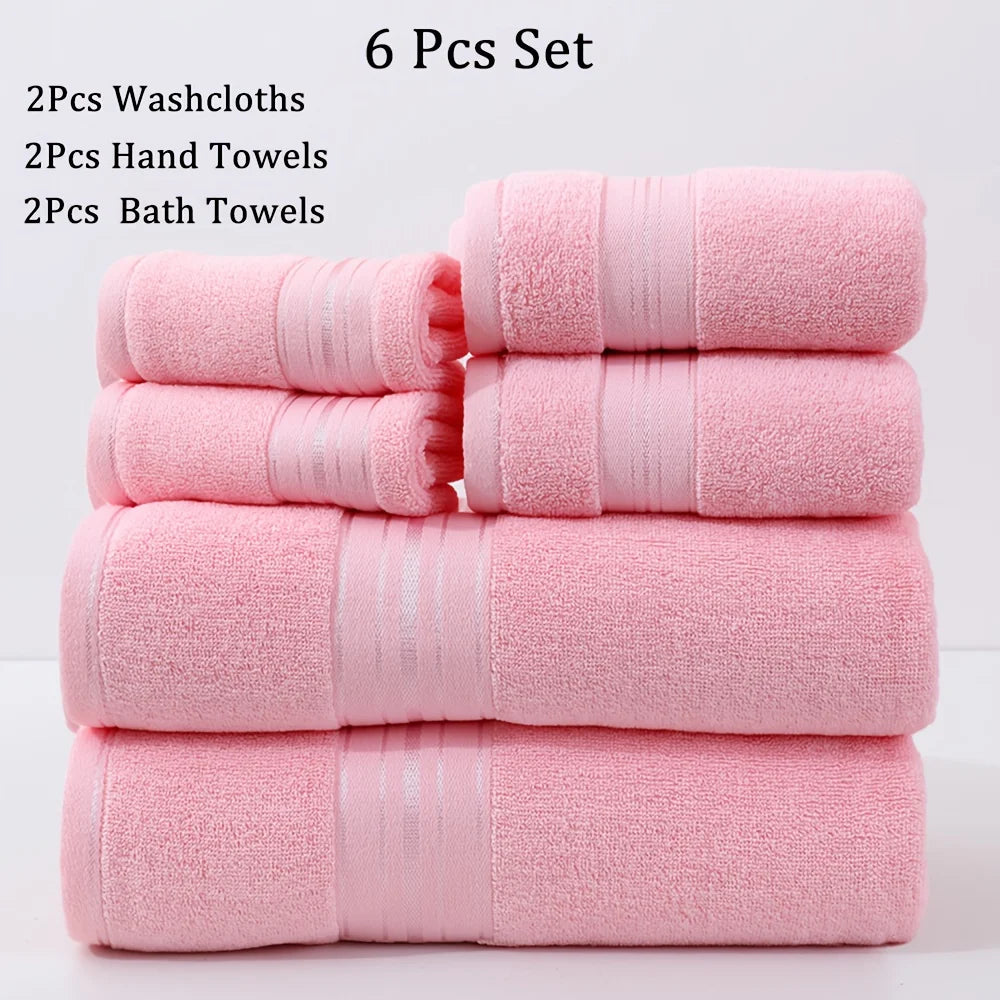 Set of pink towels including washcloths, hand towels, and bath towels on a light gray background.