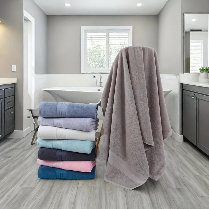 Stack of colorful towels on a wooden stool in a bathroom.