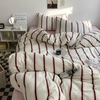 Striped bedding on a bed with a side table and decor in the background