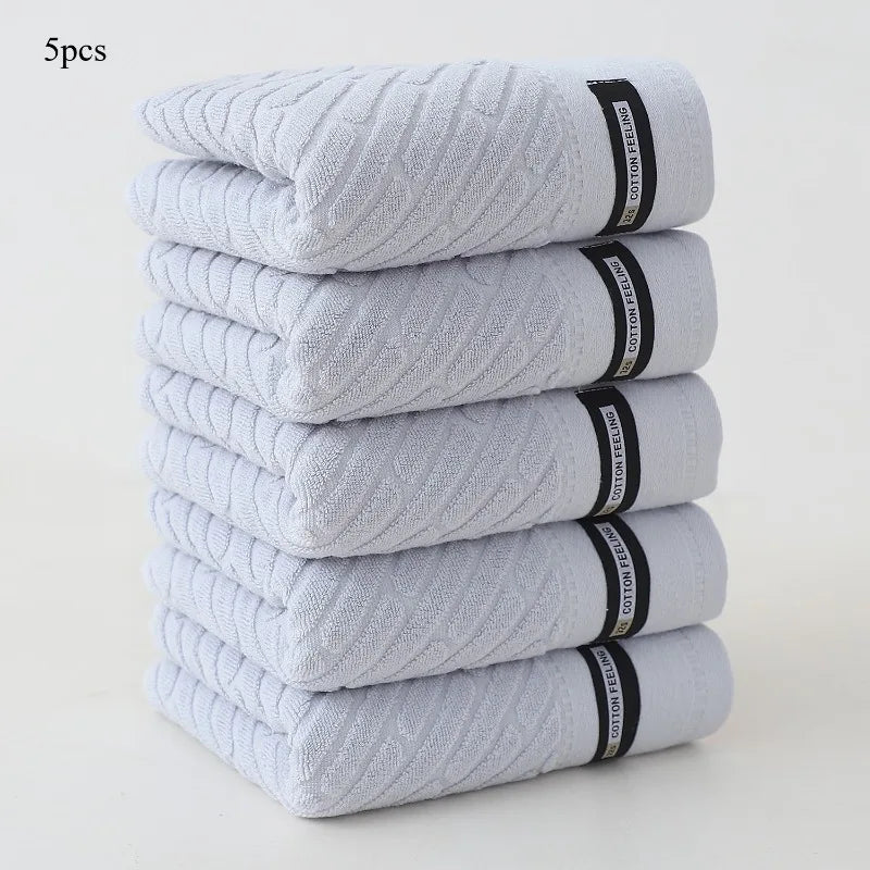 Stack of five gray towels with black labels on a white background