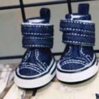 Pair of blue dog boots with white soles on a metal surface.