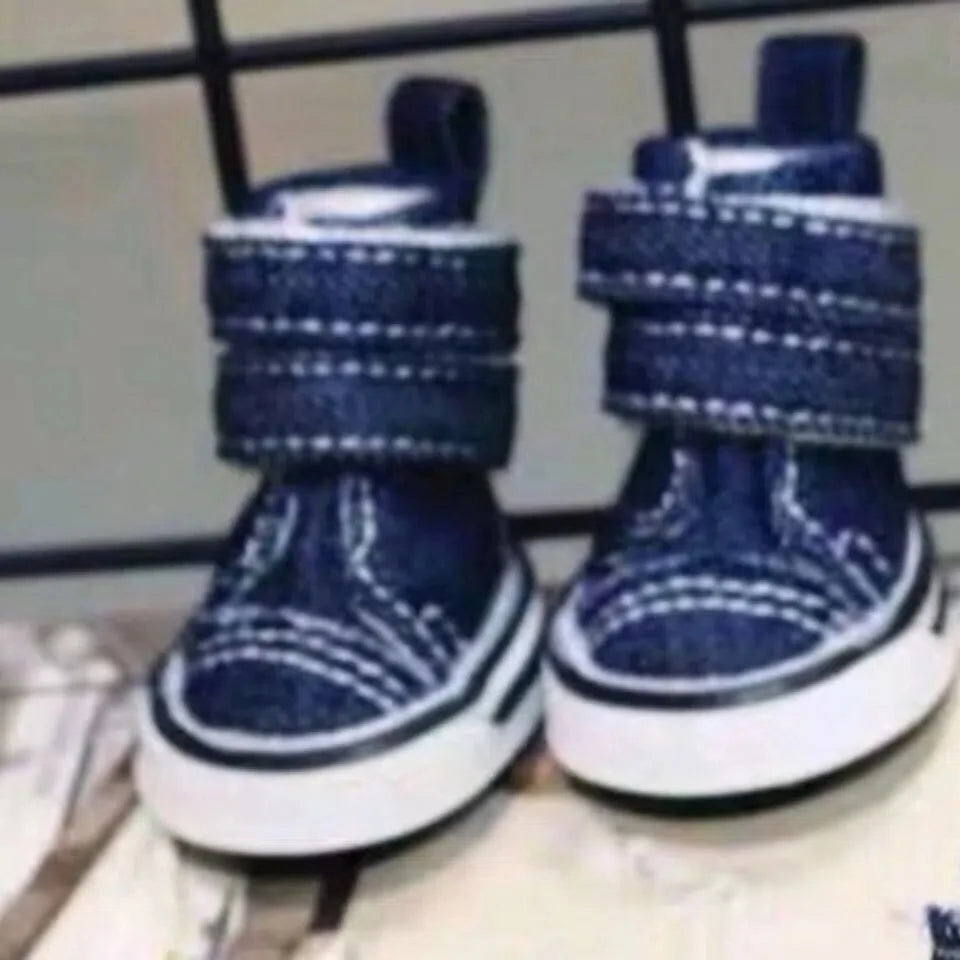 Pair of blue dog boots with white soles on a metal surface.