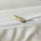 Close-up of a white garment with a gold zipper pull.