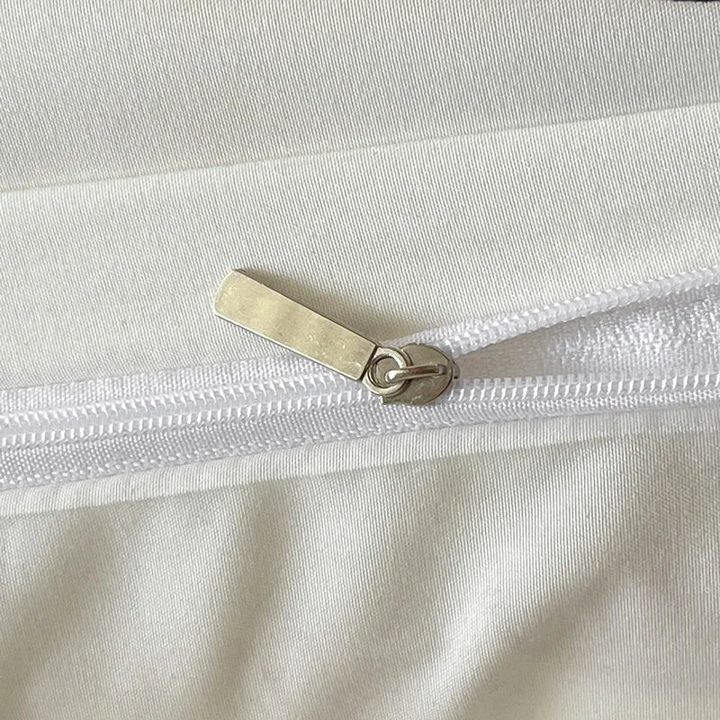 Close-up of a white garment with a gold zipper pull.