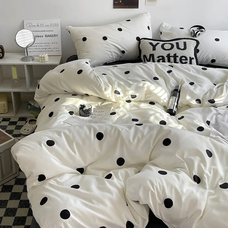 White bedding set with black polka dots on a bed in a room.