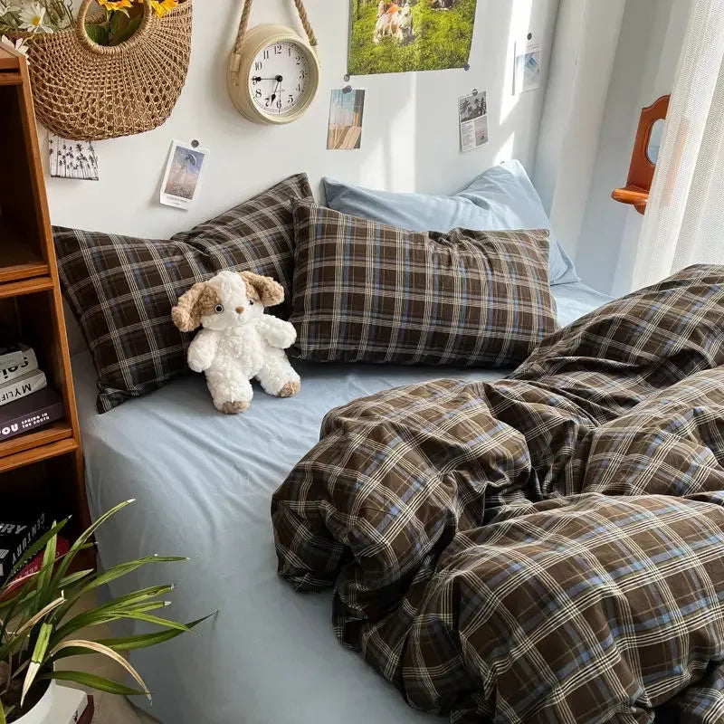 Bed with plaid bedding and pillows, teddy bear, and decorative items on a wall.