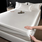 Person unrolling a silver satin sheet on a bed