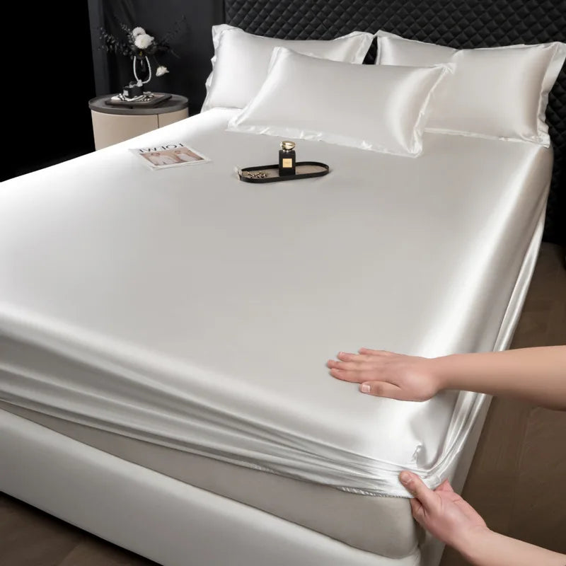 Person unrolling a silver satin sheet on a bed