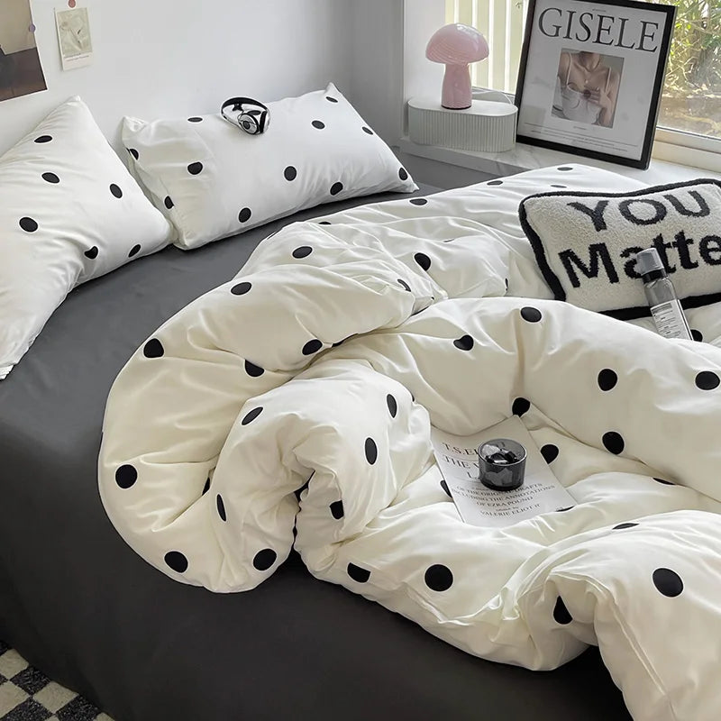 Polka dot comforter on a bed with pillows and a lamp in the background