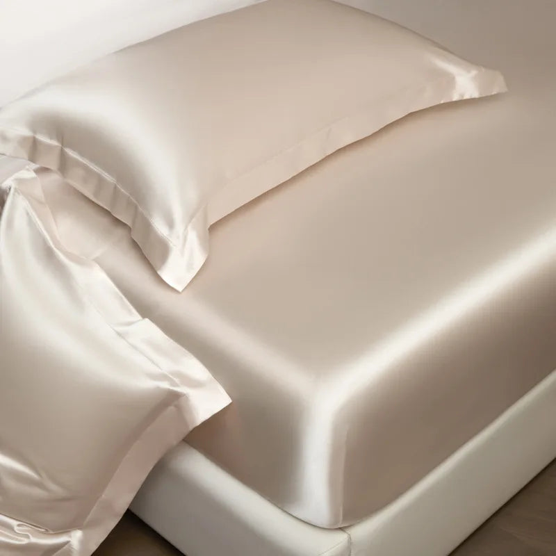 Beige satin pillowcases on a bed with a neutral background