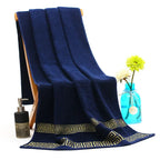 Navy blue towel with gold patterns draped over a chair, with a bottle and vase in the background.