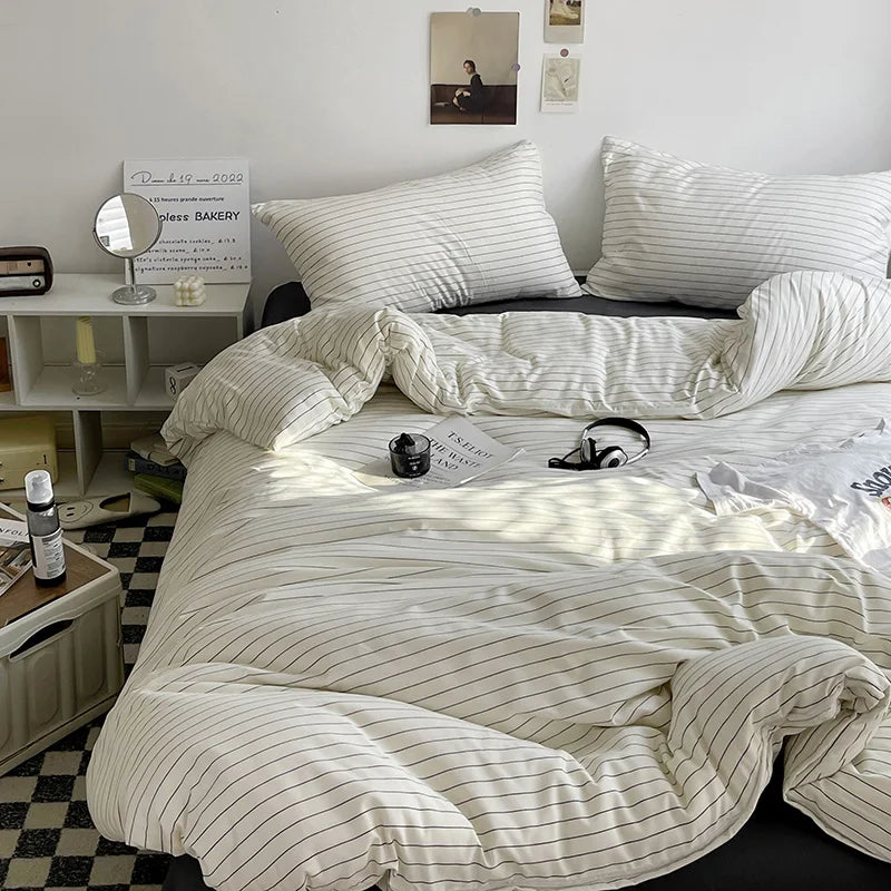 Striped bedding set on a bed in a bedroom with a mirror and books on a shelf.
