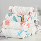Stack of colorful baby blankets with cartoon designs on a light gray background