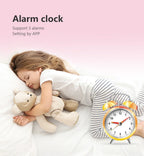 Child sleeping with a teddy bear next to an alarm clock on a pink background