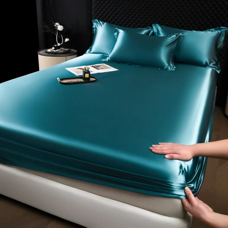 Teal satin sheet set on a bed with a person touching it