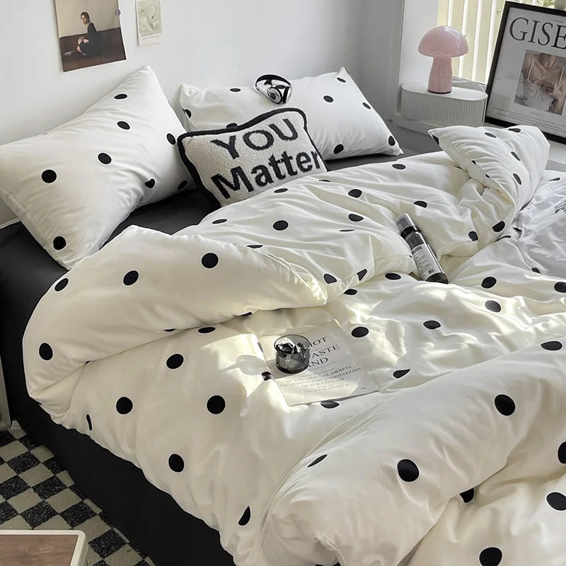 White bedding set with black polka dots on a bed in a room.