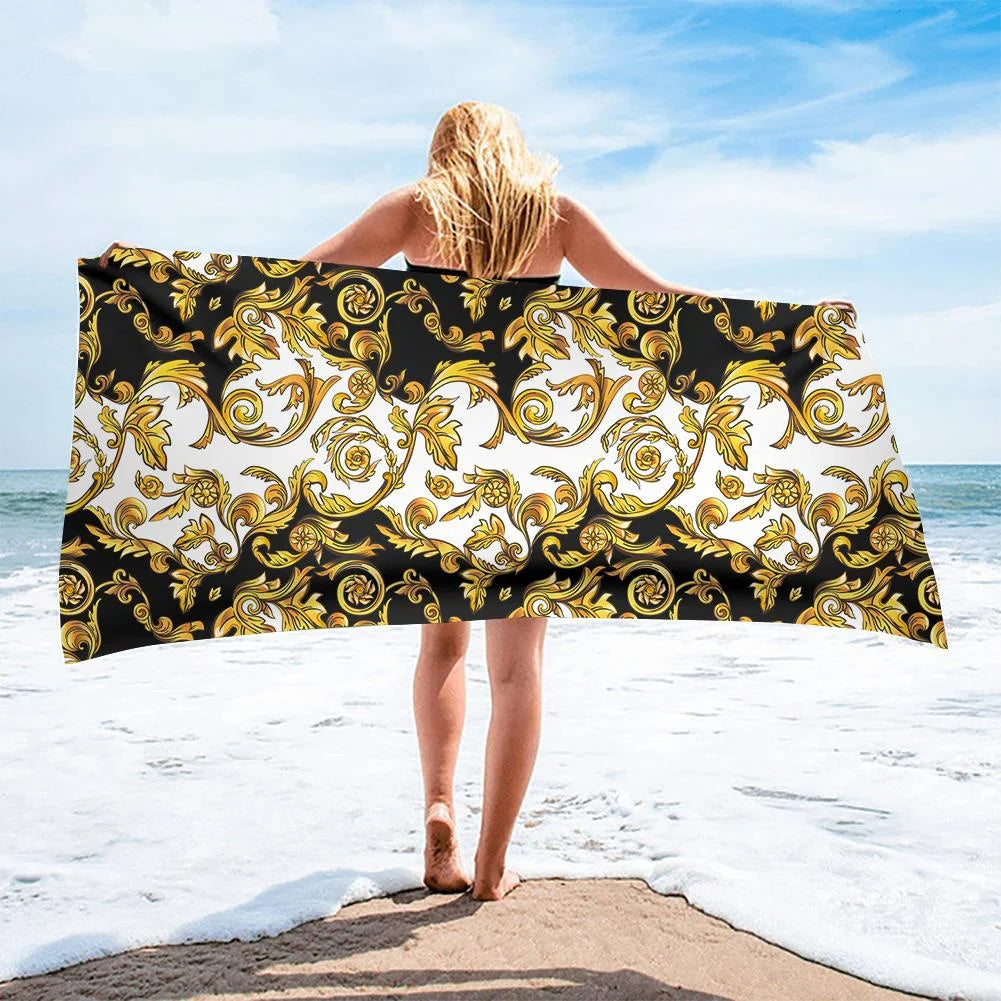 Person holding a decorative towel with gold patterns on a beach