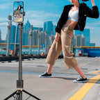 Person using a smartphone on a selfie stick with a cityscape background