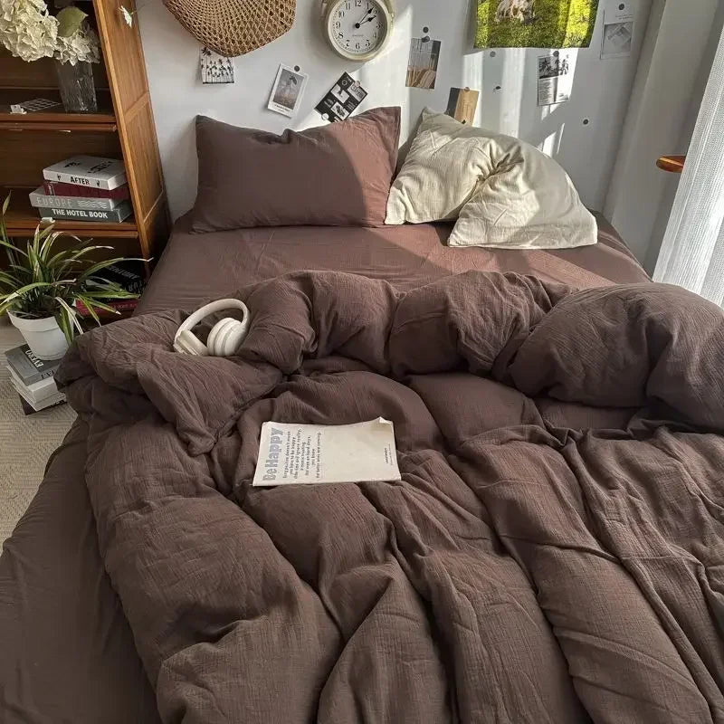 Bed with brown bedding, a book, and headphones on a wooden shelf with decor items.