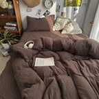 Bed with brown bedding, a book, and headphones on a wooden shelf with decor items.