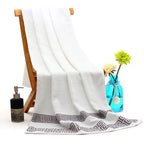 White towel draped over a wooden chair with a blue vase of flowers and soap dispenser on a white background
