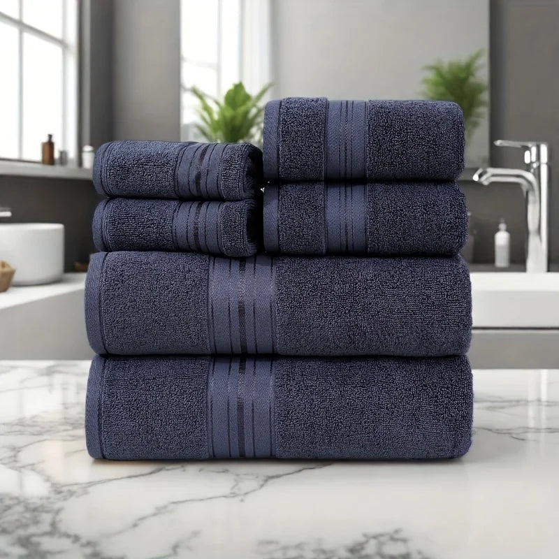 Stack of navy blue towels on a marble countertop with a bathroom setting in the background.