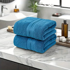 Two blue towels stacked on a marble countertop in a bathroom setting.