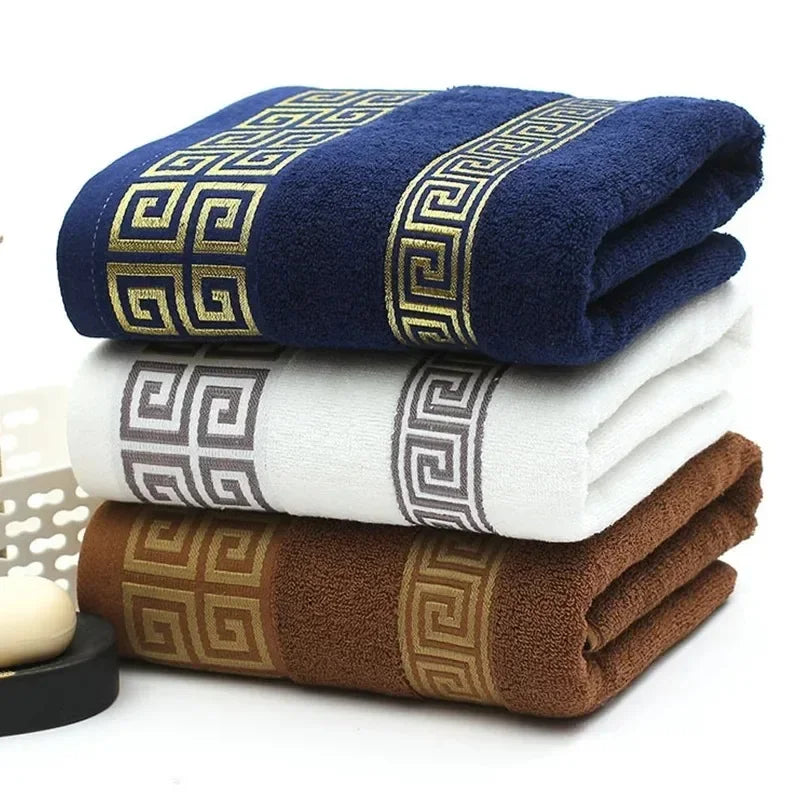 Three folded towels in blue, white, and brown with decorative patterns on a white background.