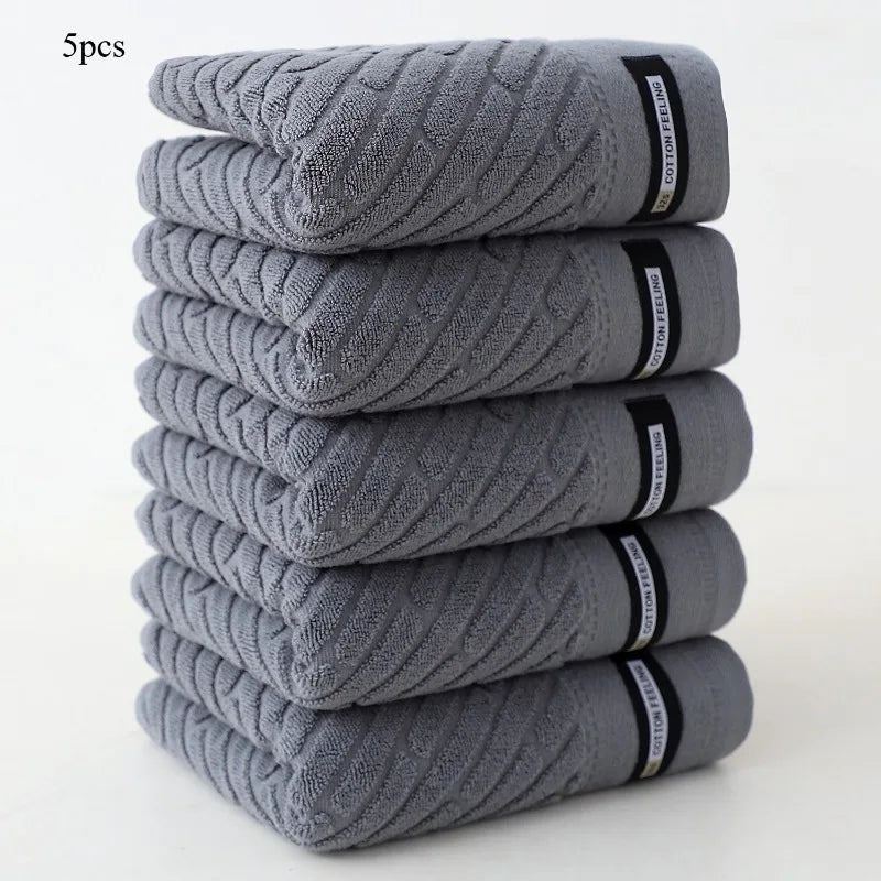 Stack of five gray towels with brand labels on a white background