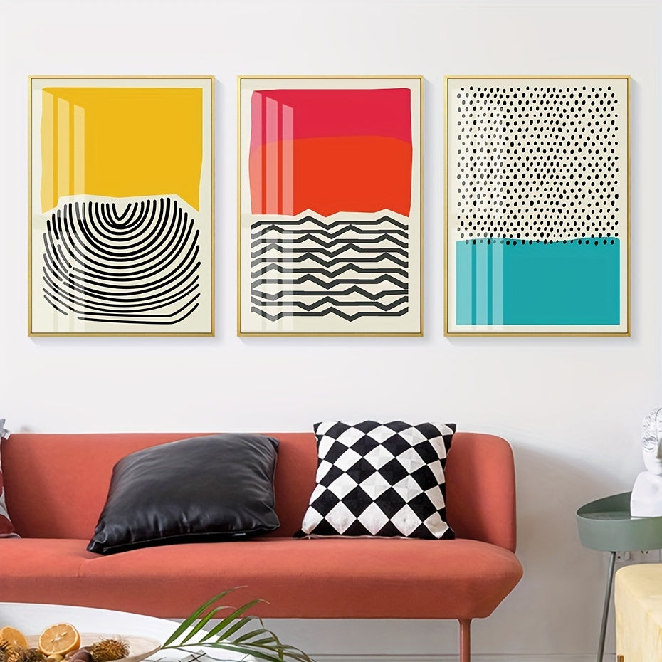 Three abstract art prints on a wall above a red sofa with decorative pillows.