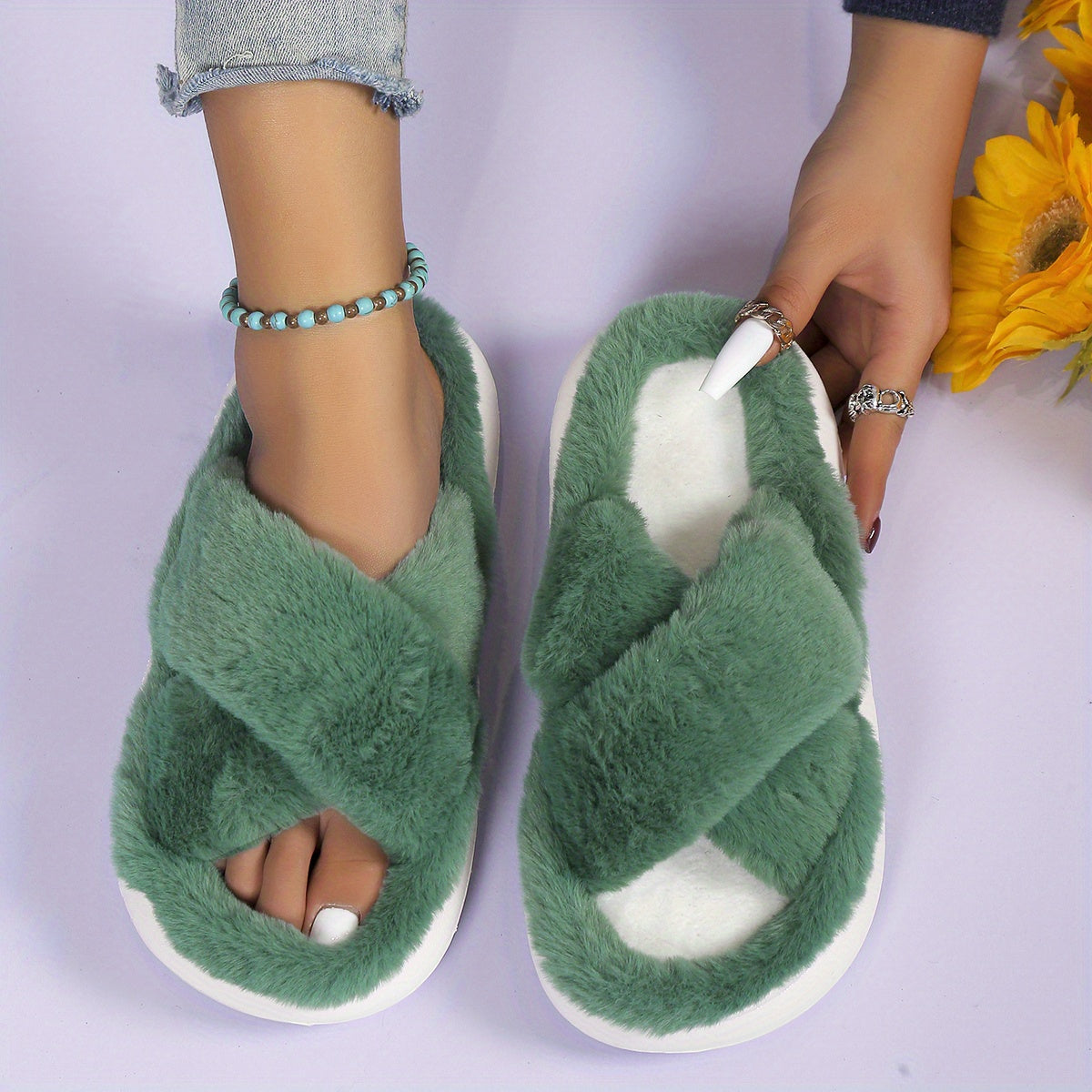 Green fuzzy slippers worn by a person on a light purple background