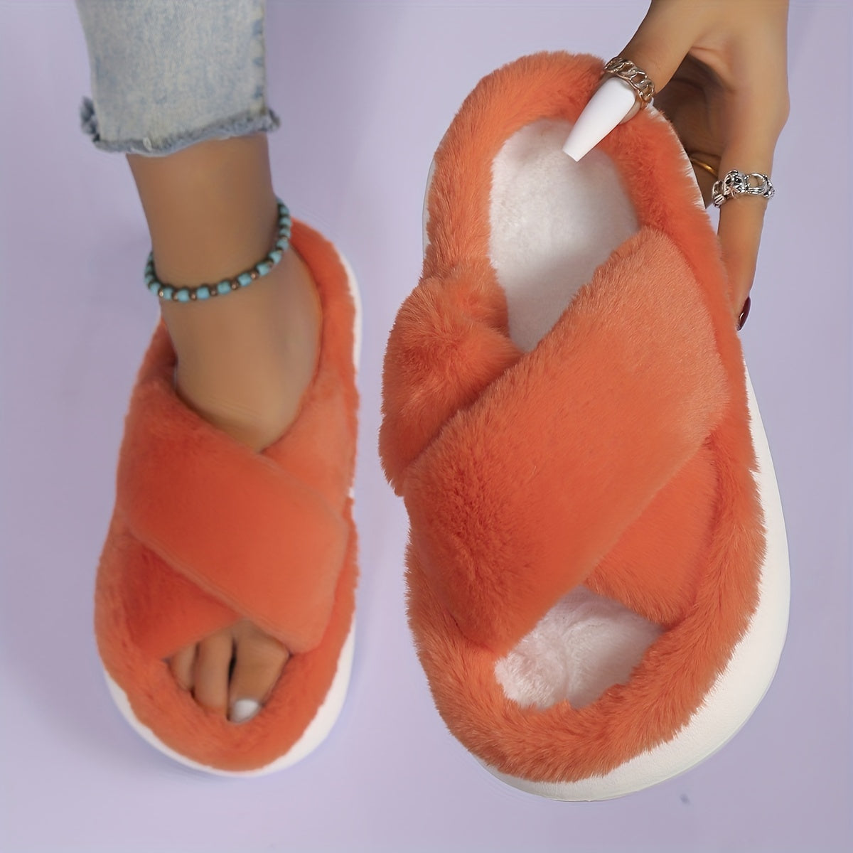 Orange fluffy slippers worn by a person on a light purple background