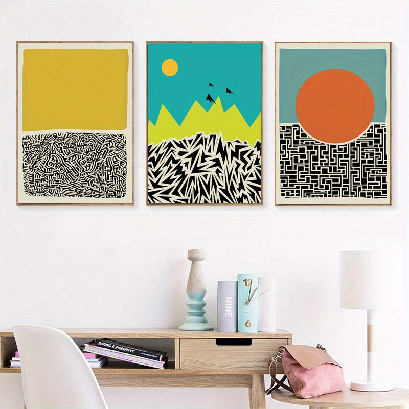 Three abstract art prints on a wall above a wooden desk.