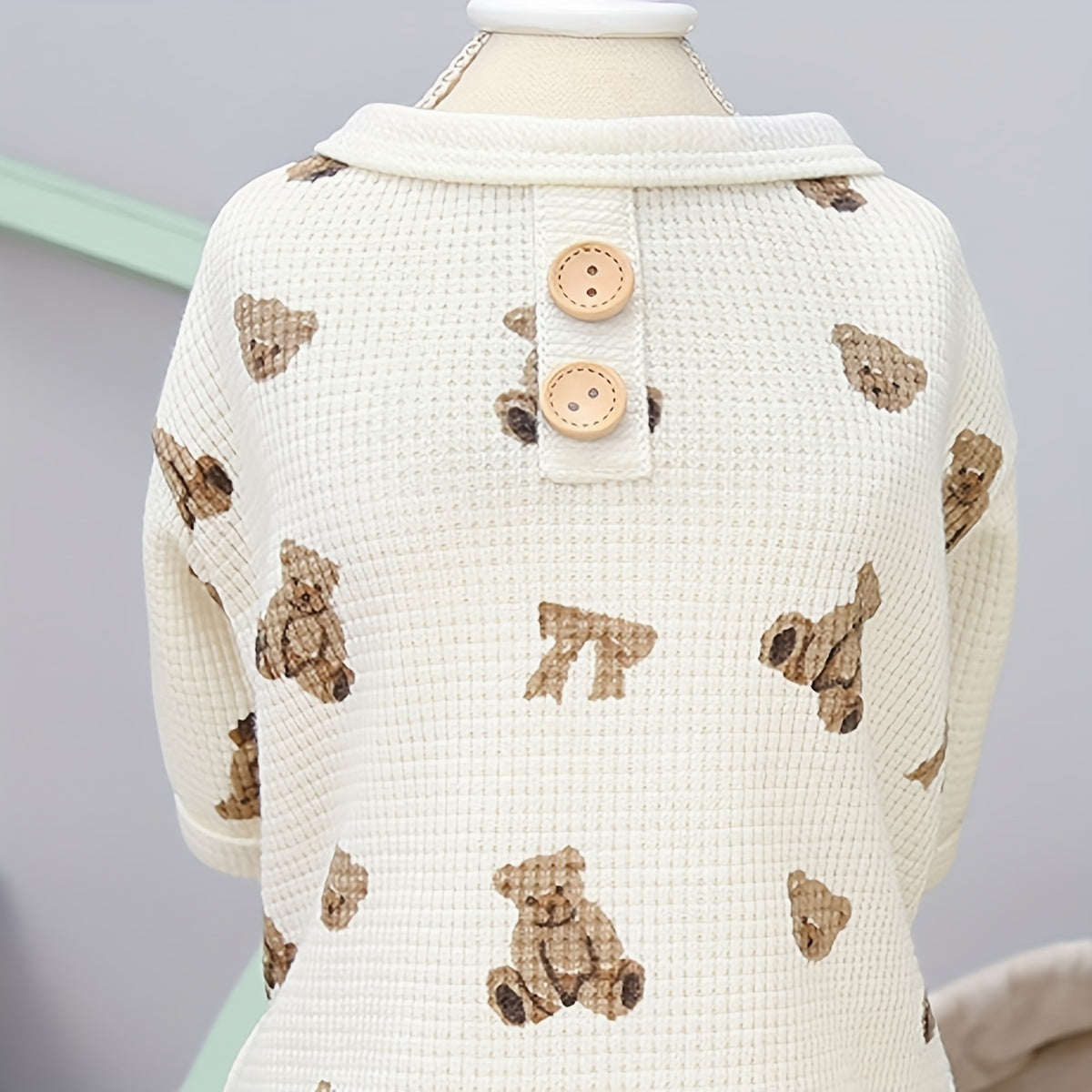Baby sweater with teddy bear pattern on a mannequin against a gray background